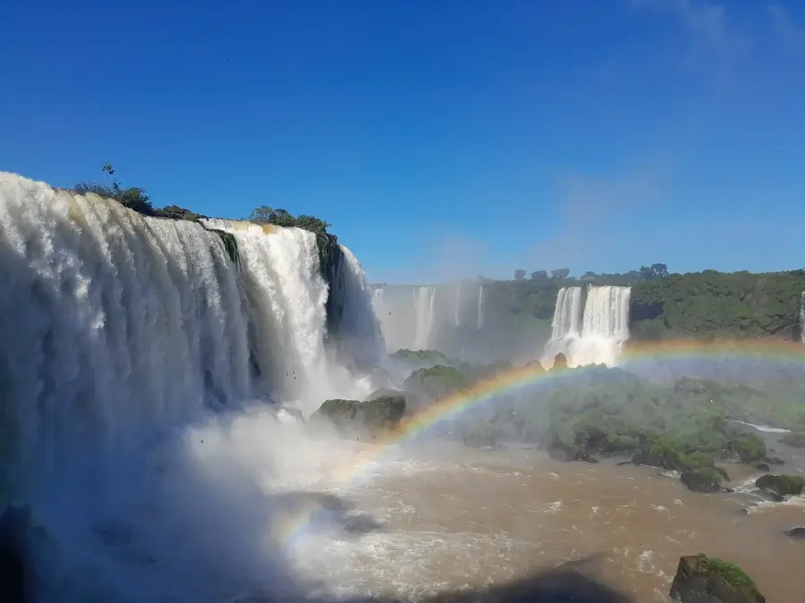 Panorama das Cataratas do Iguaçu com arco-íris sobre as quedas d’água.