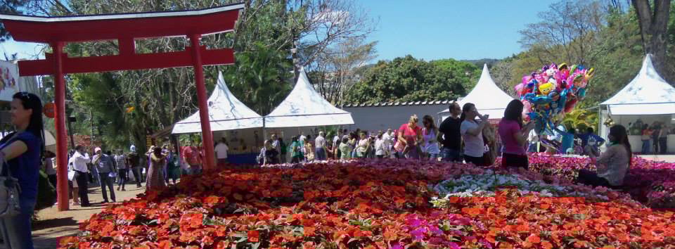 Festa do Morango de Atibaia com decoração de flores, além de barraquinhas e pessoas participantes.