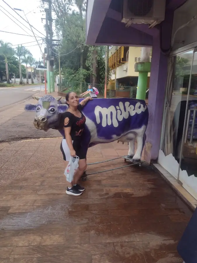 Marcia Lira abraçando a famosa vaca roxa da Milka em frente a uma loja da Milka em Puerto Iguazú, Argentina.