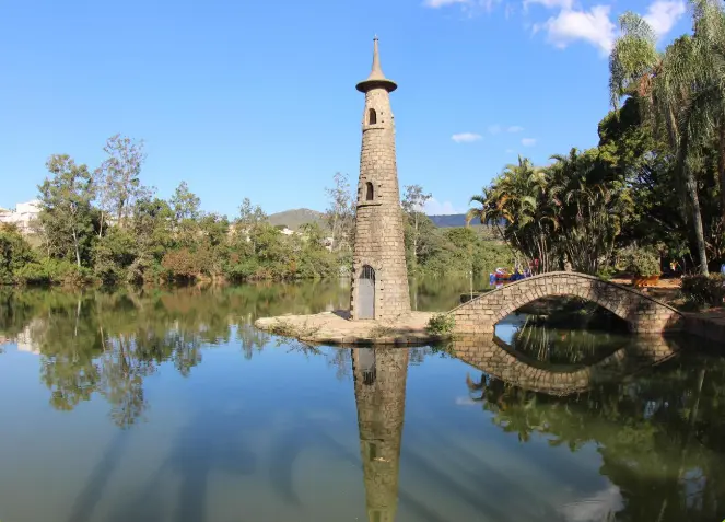 Vista da torre do Parque Edmundo Zanoni, com o lago, as árvores e as montanhas ao entorno.