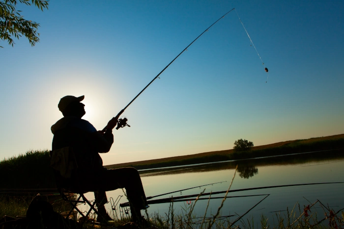 Homem pescando ao entardecer, representando os pesqueiros de Atibaia.
