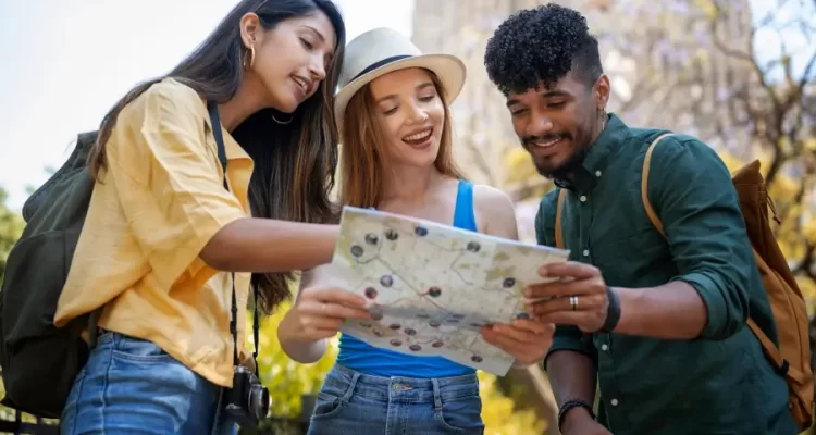 Três pessoas escolhendo um roteiro de viagem a partir de um mapa impresso, representando a escolha do que fazer em Atibaia em um dia ou em dois dias. Fonte: Freepik.