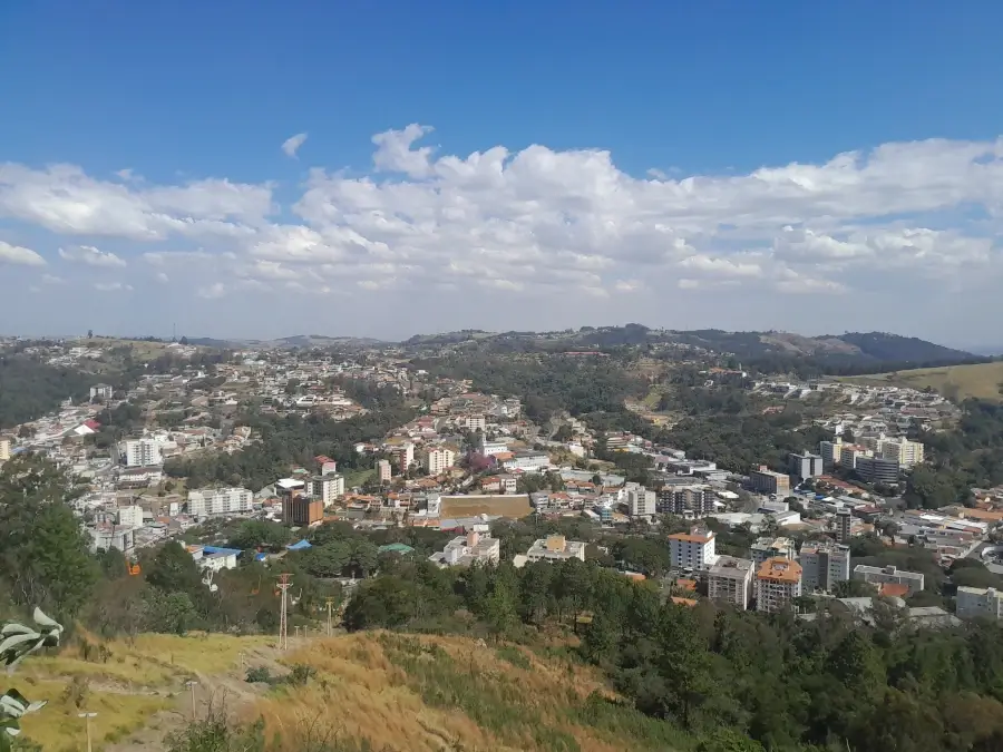 Vista panorâmica de Serra Negra do Mirante do Cristo, mostrando a cidade e as colinas ao redor em um dia de sol.