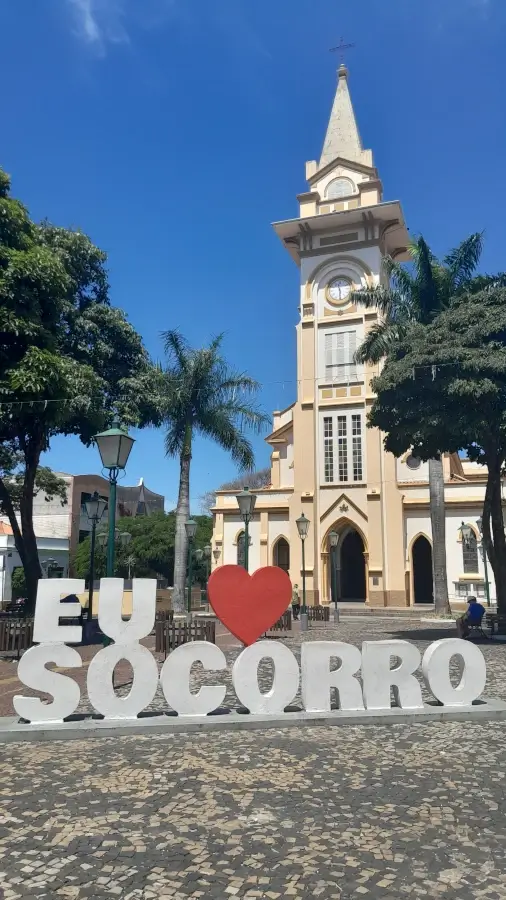 Fachada da Igreja Matriz Nossa Senhora do Perpétuo Socorro em um dia de céu azul, com o letreiro “Eu amo Socorro” em primeiro plano.