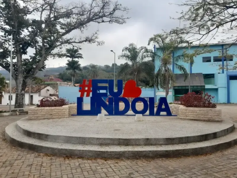 Letreiro turístico "#EuAmoLindoia" em uma praça arborizada na cidade de Lindóia, no Circuito das Águas.