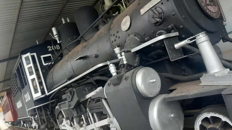 Close-up da lateral da locomotiva a vapor preta, modelo 208, da Maria Fumaça de Socorro–SP.