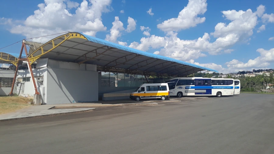 Pátio do terminal rodoviário de Socorro, SP, com ônibus de viagem estacionados em um dia ensolarado.