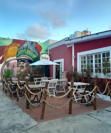 Fachada externa do restaurante Casa do Pará em João Pessoa, com mesas de madeira na calçada e um grande mural colorido de um indígena na parede lateral.