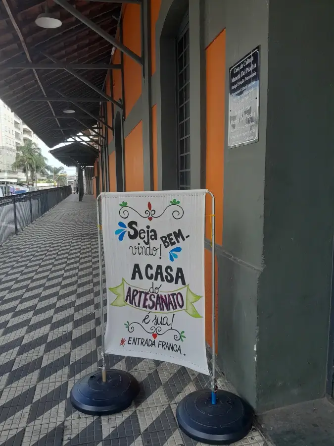 Entrada da Casa da Cultura Menotti Del Picchia, prédio histórico laranja com banner convidando para a Casa do Artesanato.