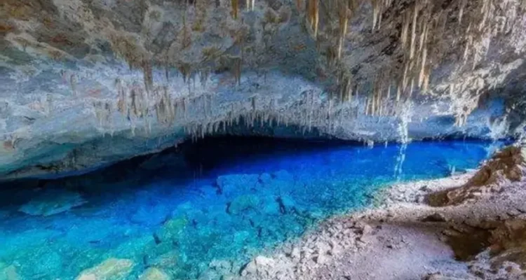 Foto de uma gruta na região de Bonito (MS). A água é azul cristalina e o teto da gruta possui Estalactites.