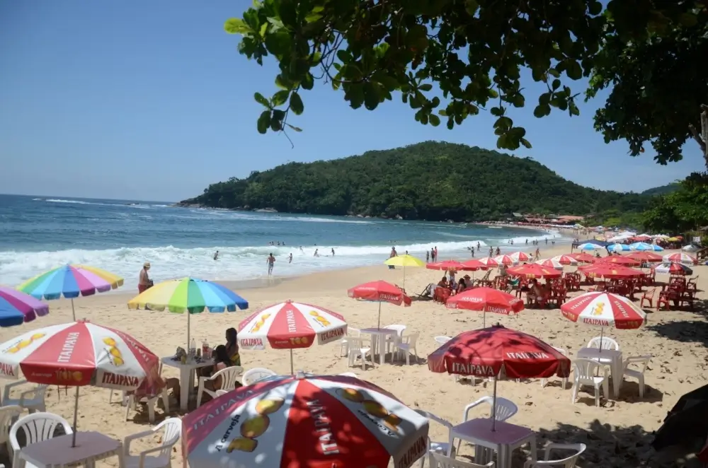 Praia dos ranchos, em Trindade, Rio de janeiro. O dia está ensolarado e várias pessoas estão curtindo a praia com guarda-sóis
