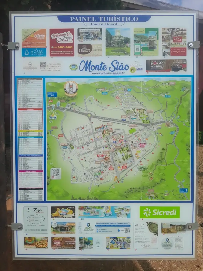 Painel turístico vertical de Monte Sião com mapa ilustrado das ruas do centro, pontos de interesse e anúncios de comércios locais.